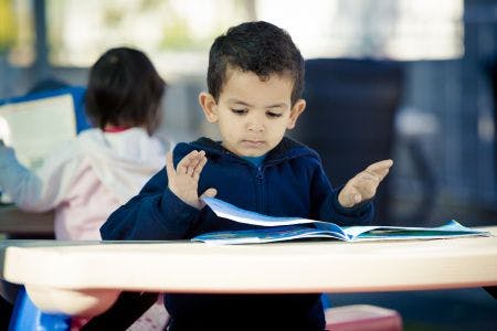 Child reading a book at a table