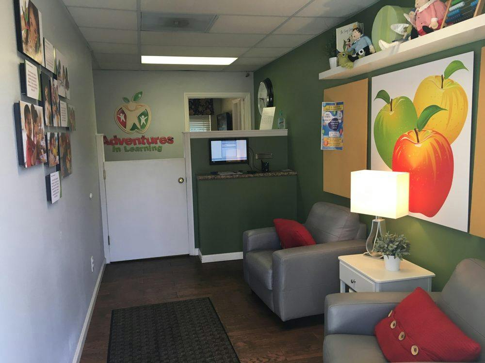 Waiting room with two armchairs, a side table with a lamp, and apple artwork