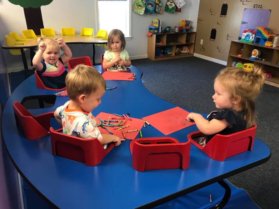 Children sitting at a table with art supplies