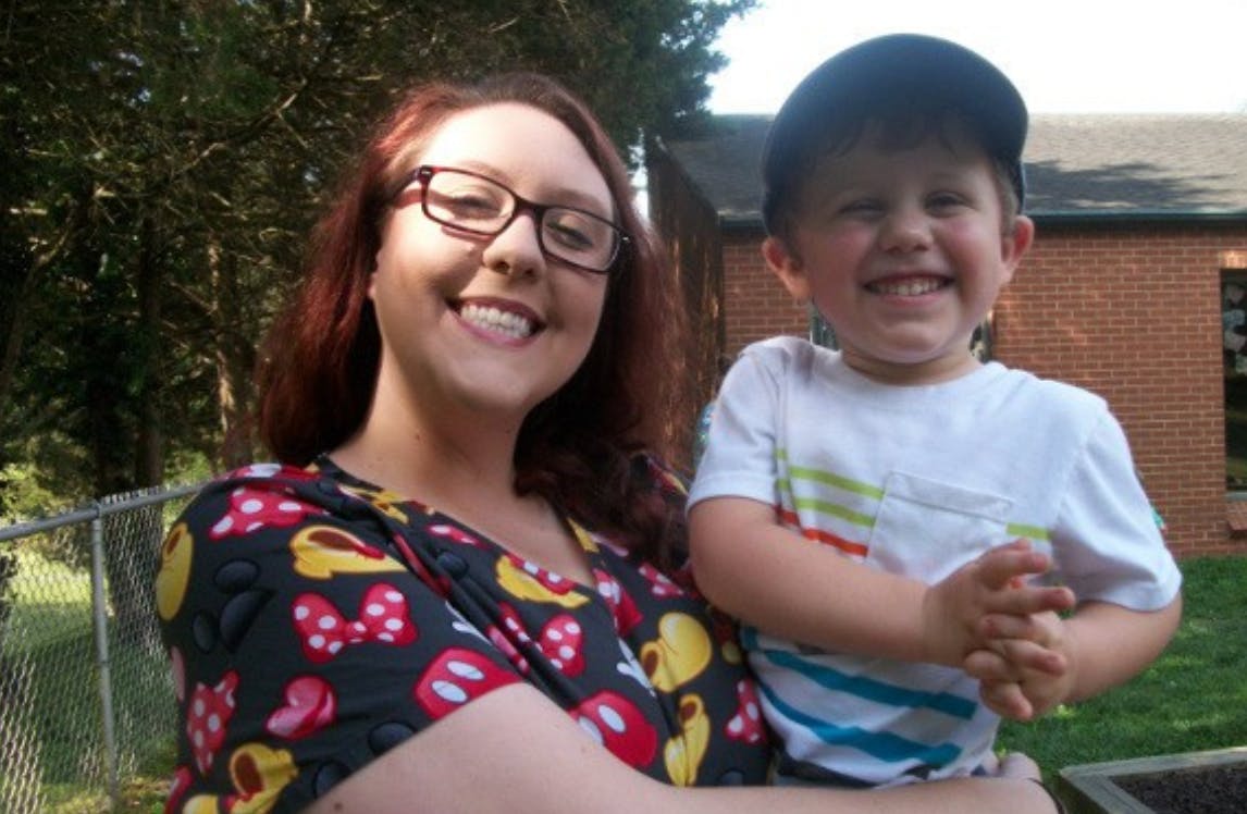 Person in glasses holding a child in a baseball cap