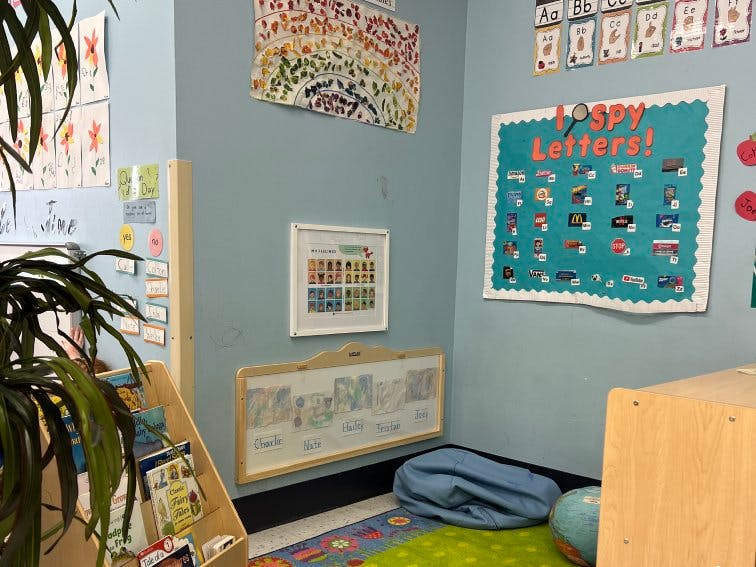 Children's classroom corner with an I Spy Letters board and book shelf