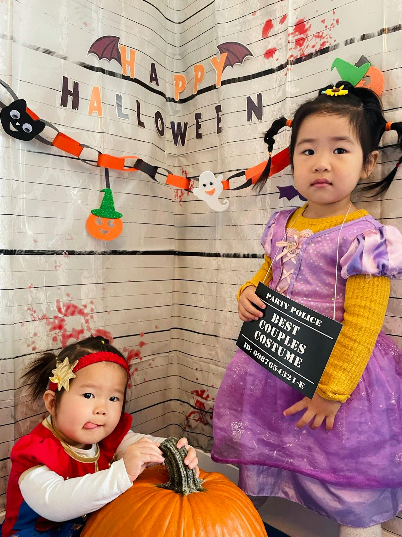 Two children with a pumpkin and Halloween decorations