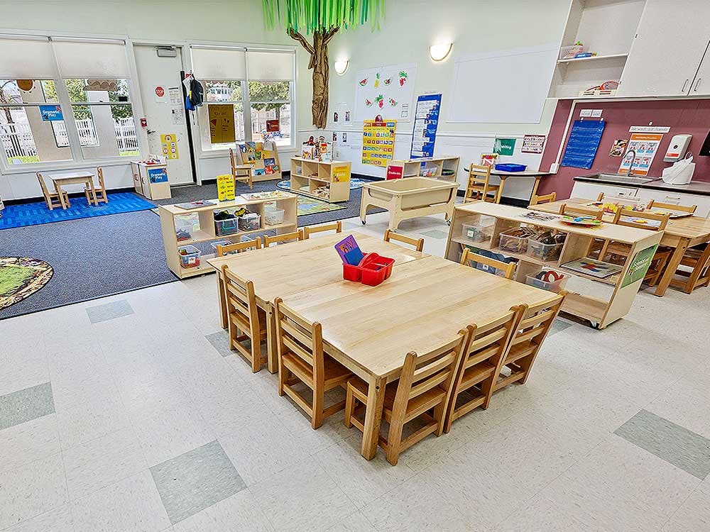 Empty preschool classroom with small tables and chairs