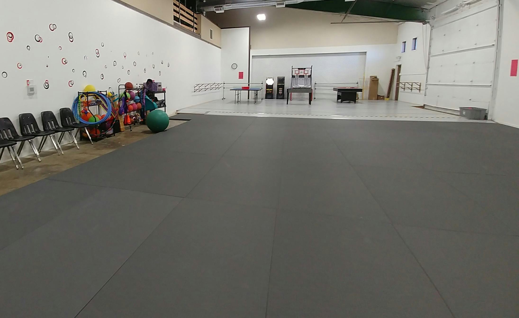 Empty room with dark gray floor mats and chairs along a white wall