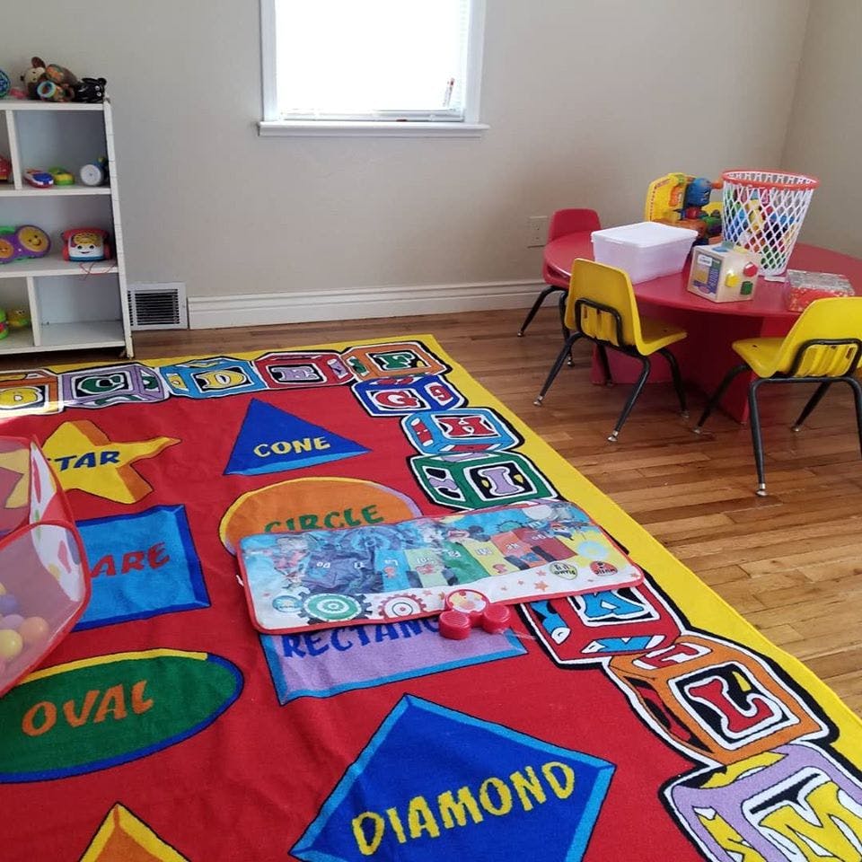 Playroom with a colorful rug, small red table, and yellow chairs