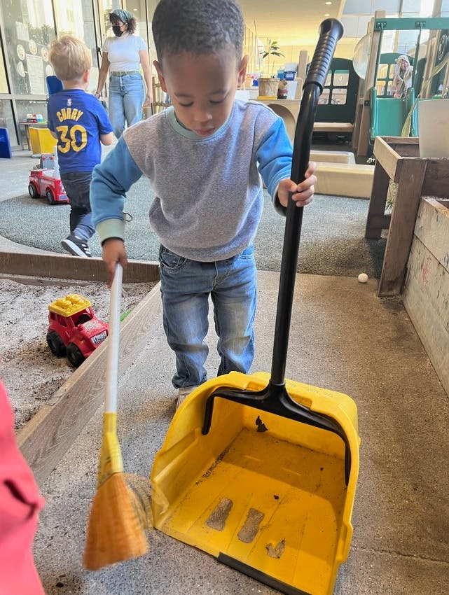 Child holding a broom and dustpan