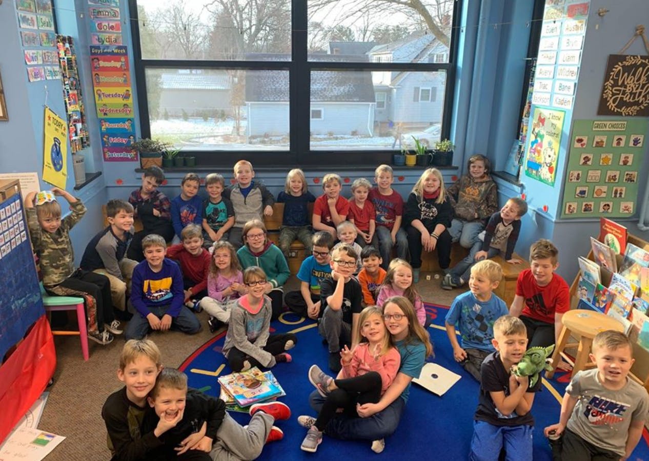 Group of children and adults sitting on the floor in a classroom