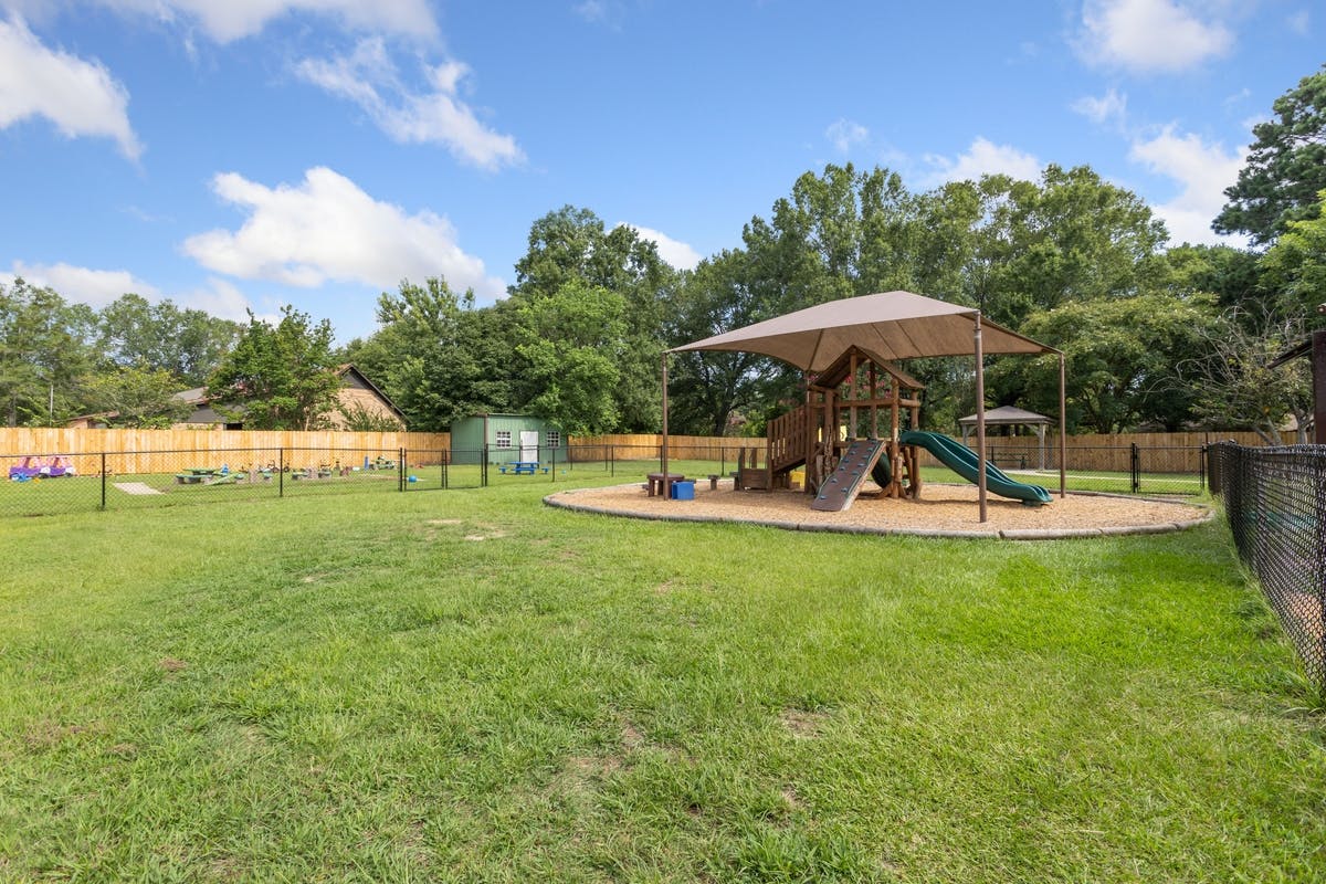 Outdoor playground area with a play structure, slide, and grass