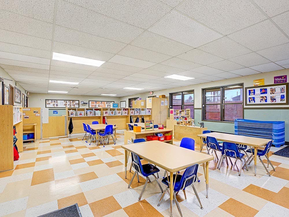 An empty classroom with small tables and chairs