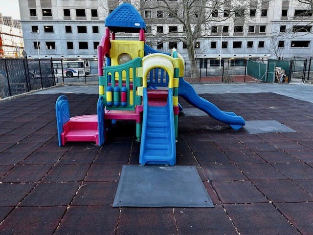 Playground structure with slides and stairs on a rubberized surface