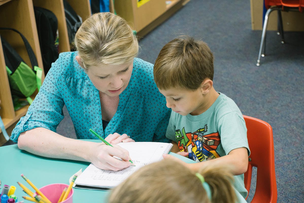 Adult and child writing in a notebook at a table