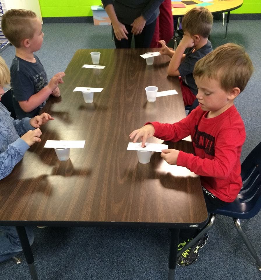 Children at a table with cups and paper