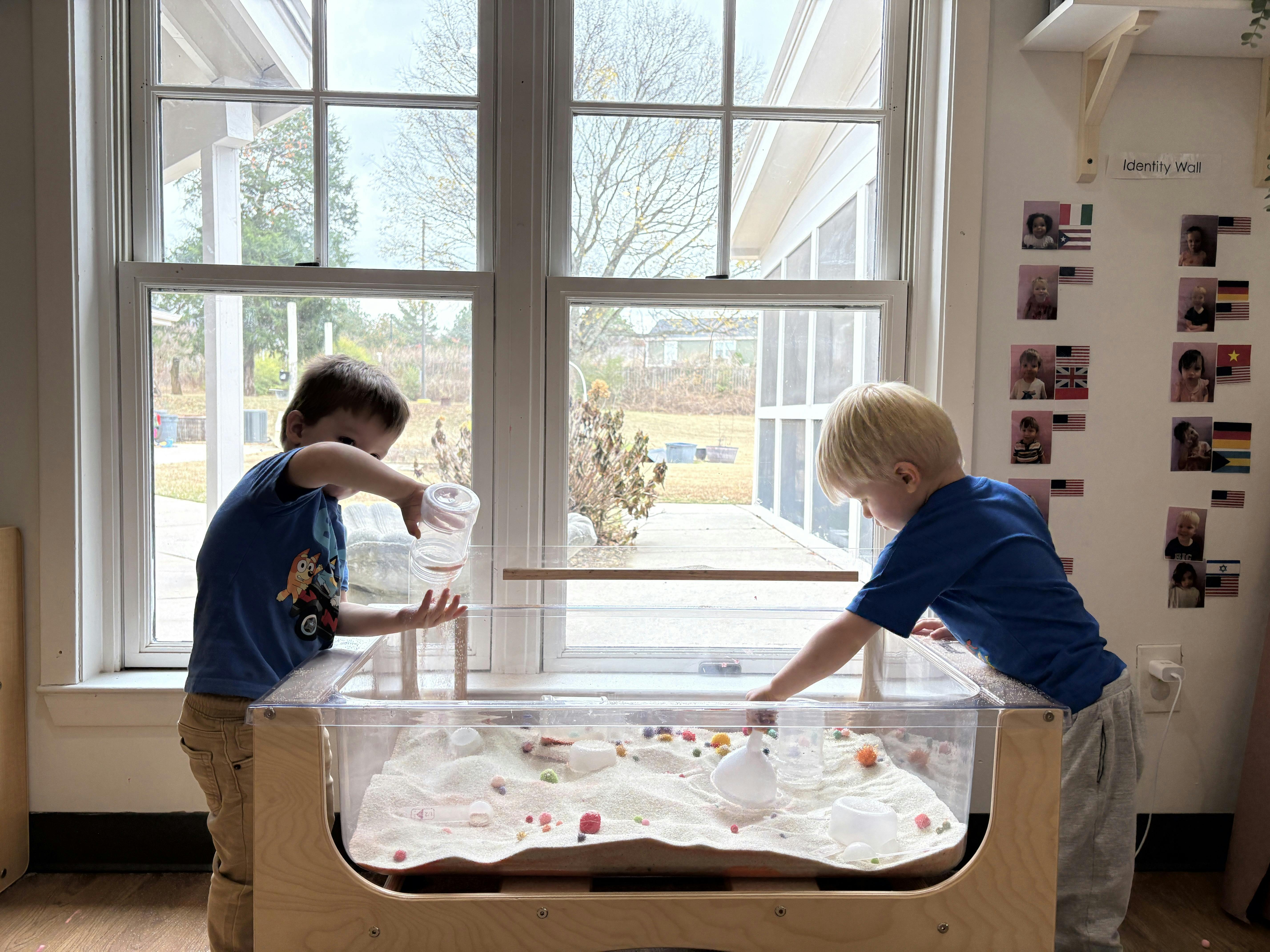 Two children playing with sand at a sand table