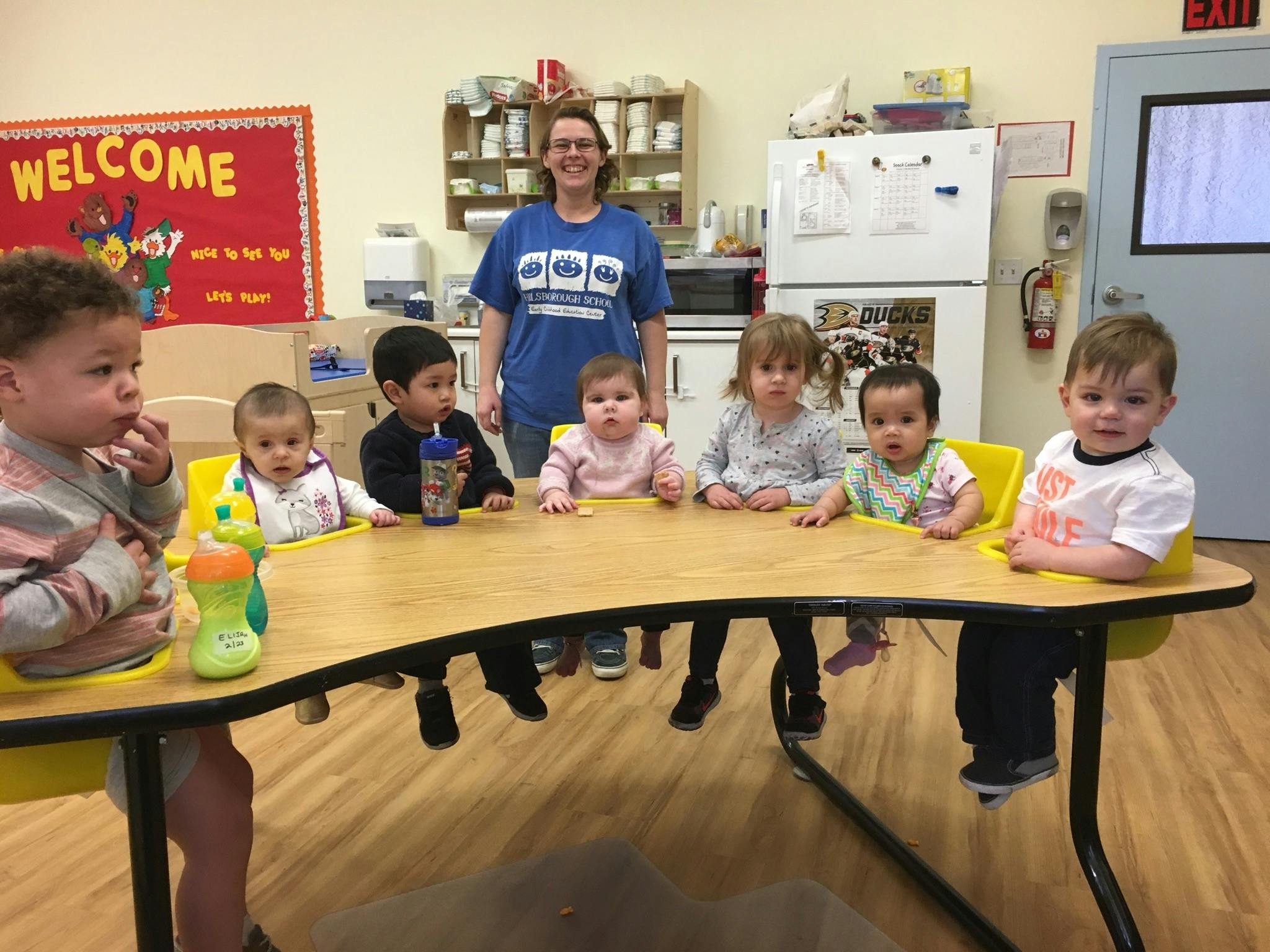 Adult and multiple children sitting at a table in a classroom