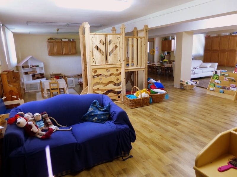 Playroom with a blue couch, wooden play structure, and baskets of toys