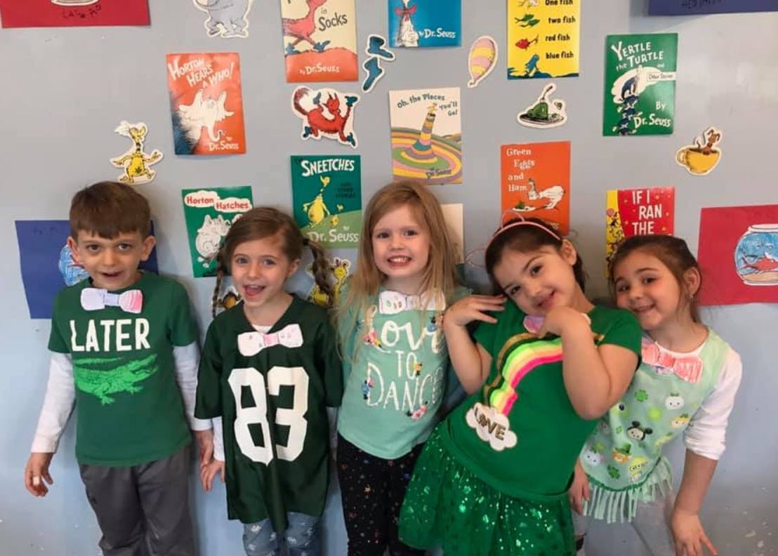 Five children standing in front of a wall with colorful decorations