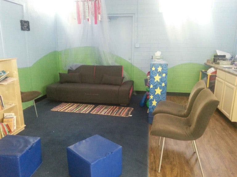 Room with a brown sofa, two chairs, and blue ottomans