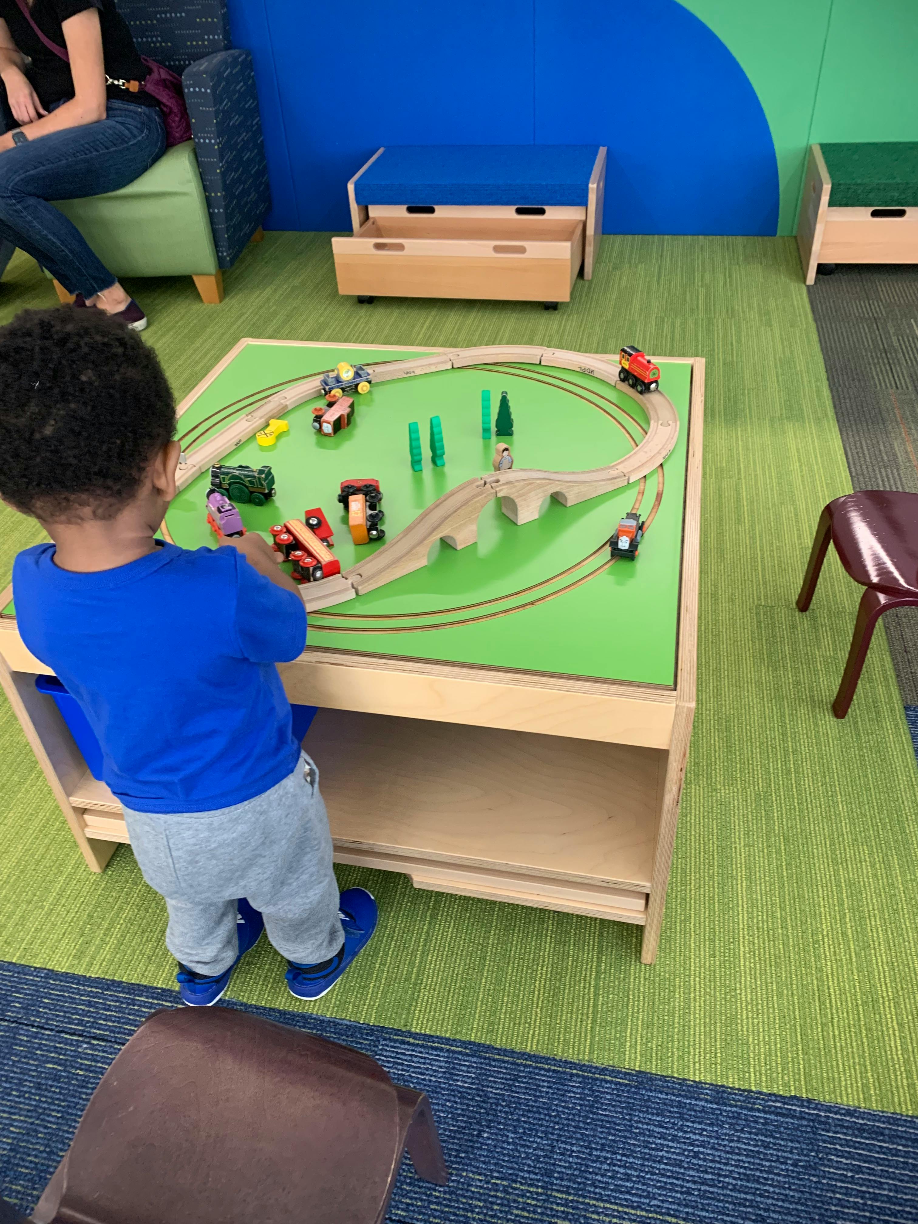 Child playing with a toy train set on a green table