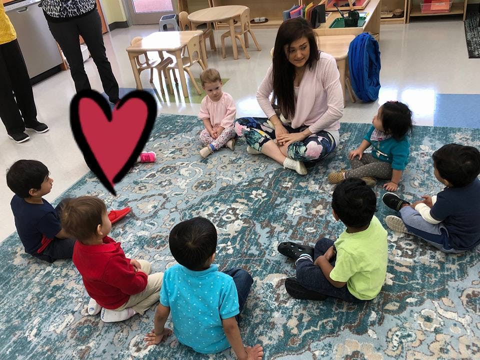 Adult and children sitting in a circle on a rug in a classroom