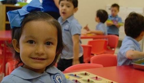Child with blue bow in a classroom with other children