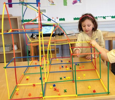 Child building a structure with colorful sticks and connectors