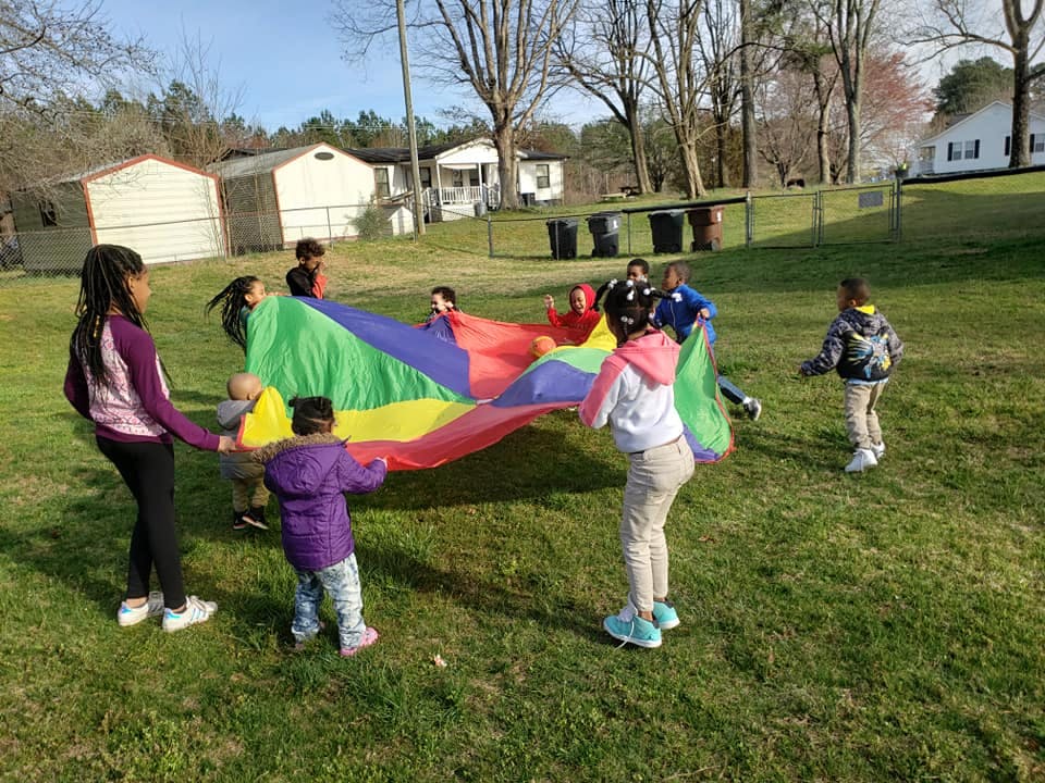 Children playing with a colorful parachute outdoors