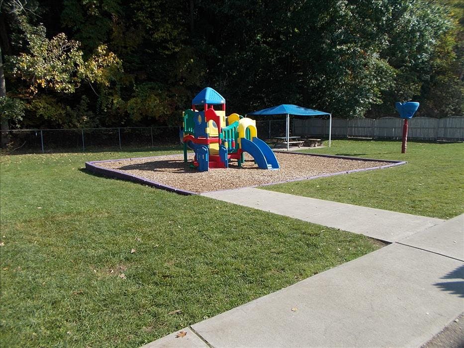Colorful playground structure on wood chips next to a picnic shelter