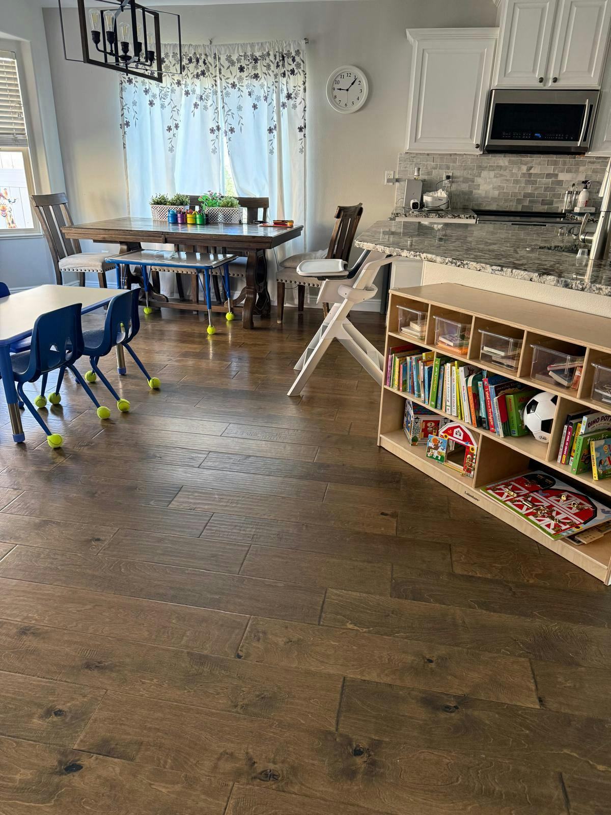 Kitchen and dining area with wooden floors and a child's bookshelf