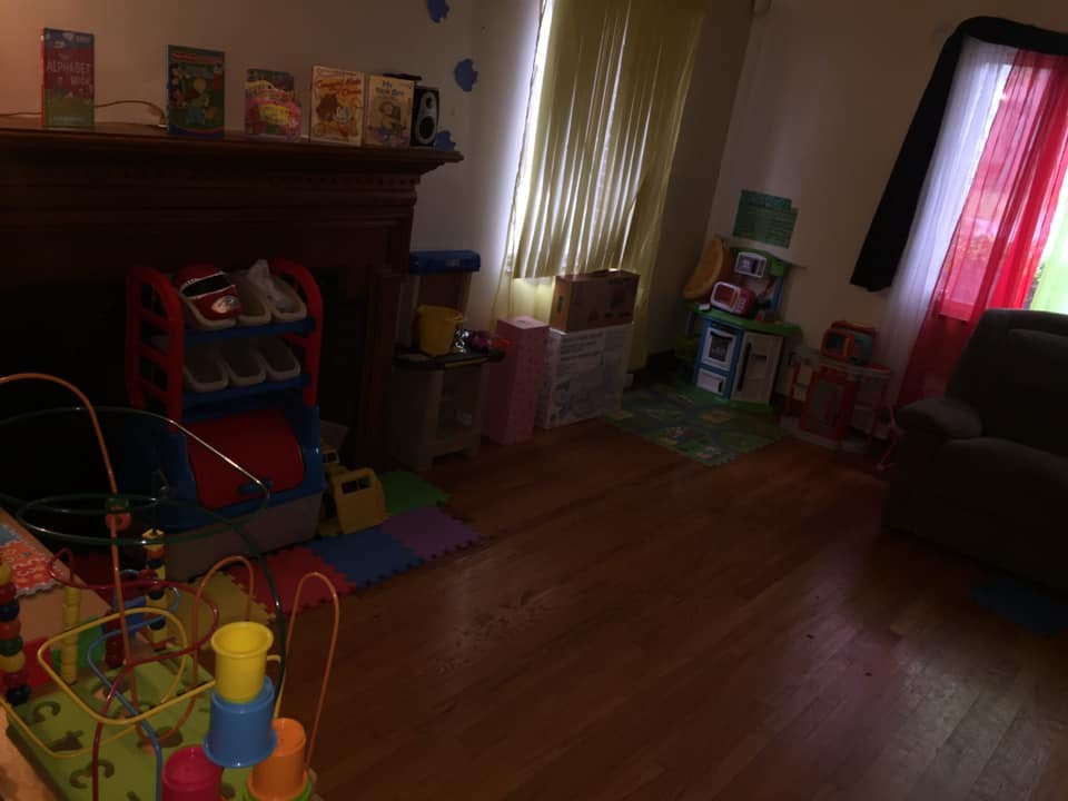 Room with hardwood floor, fireplace, and various toys and storage boxes