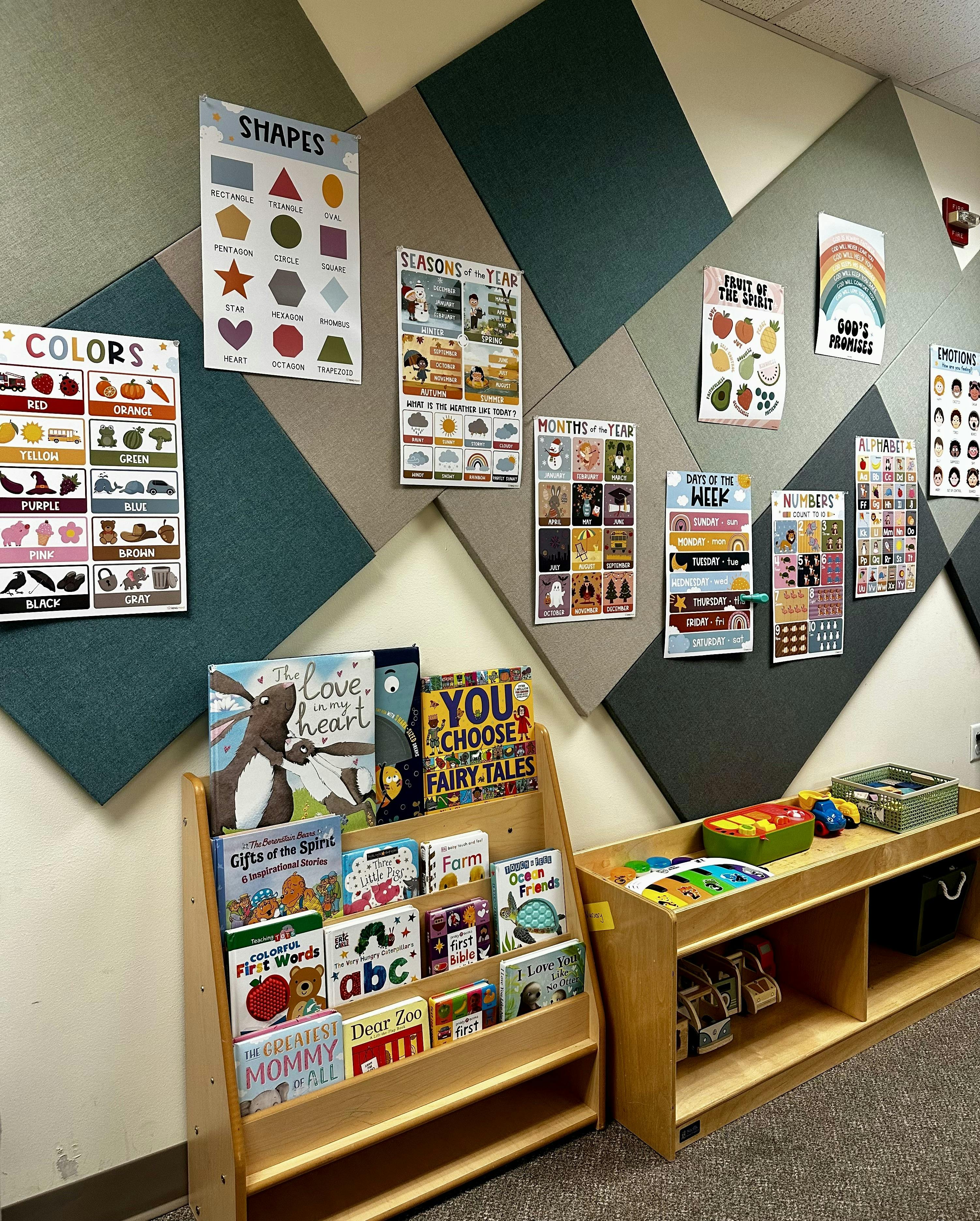 Classroom wall with educational posters and a bookshelf with children's books