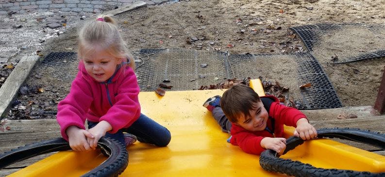 Two children playing with tires on a yellow surface