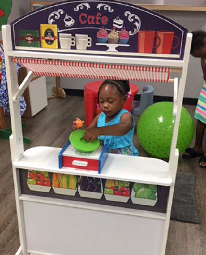 Child playing with a toy cash register at a play cafe stand