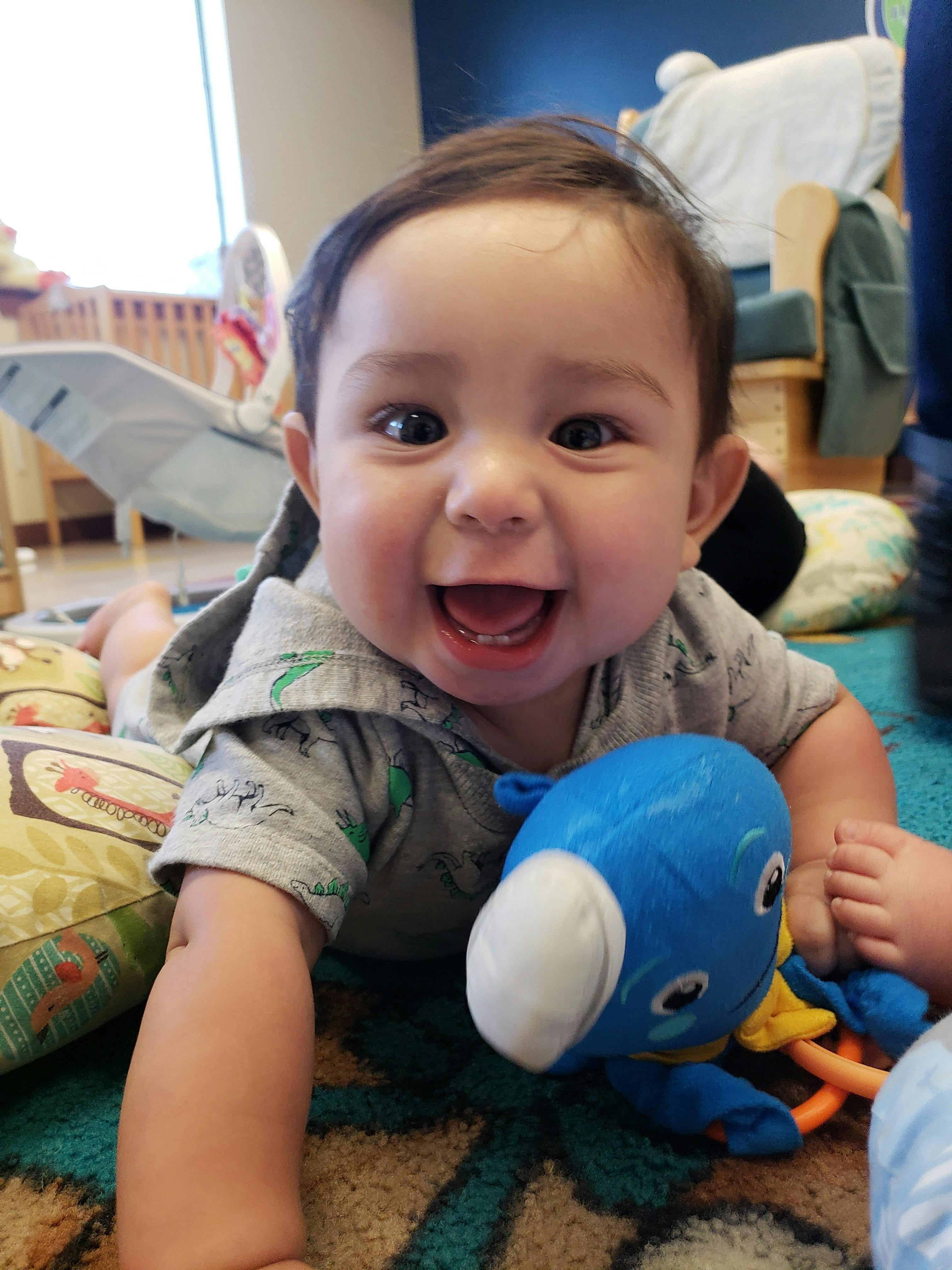 Child on stomach holding a blue toy