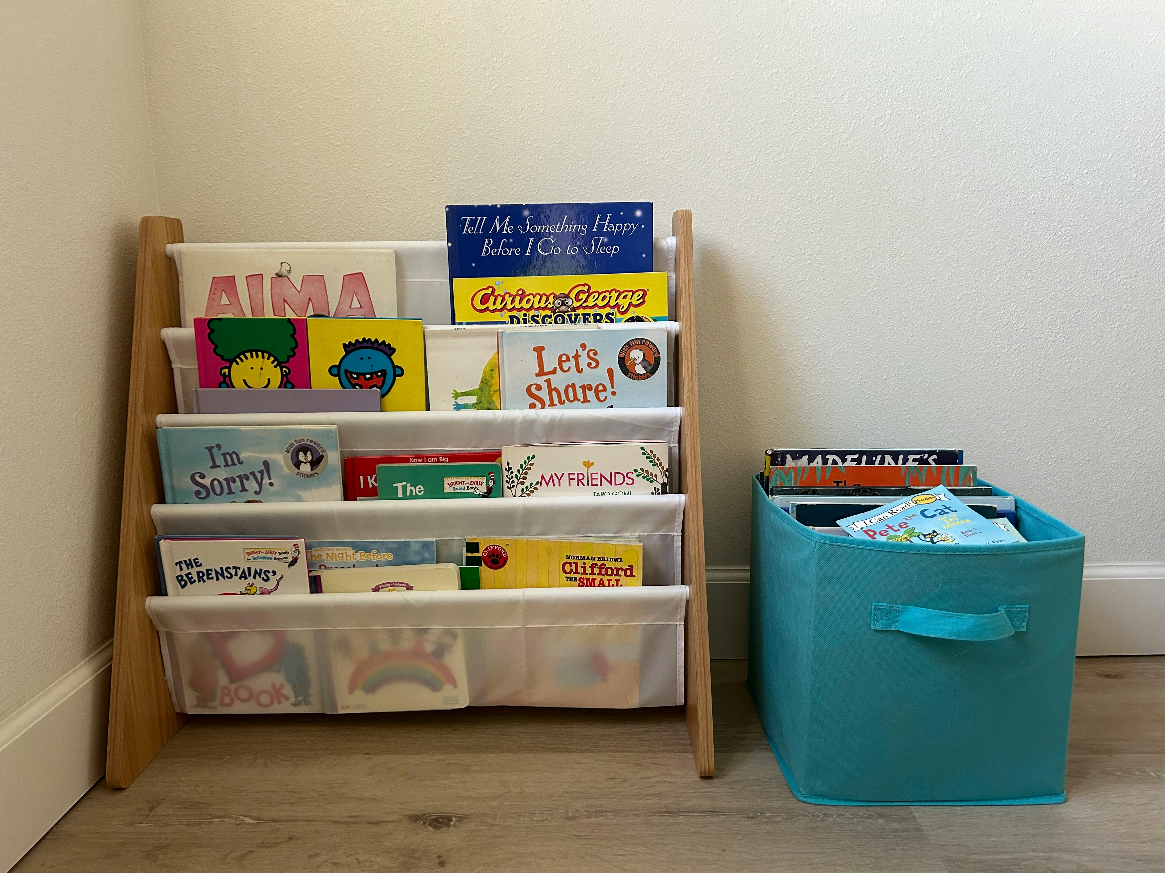Children's books on a wooden bookshelf and in a blue bin