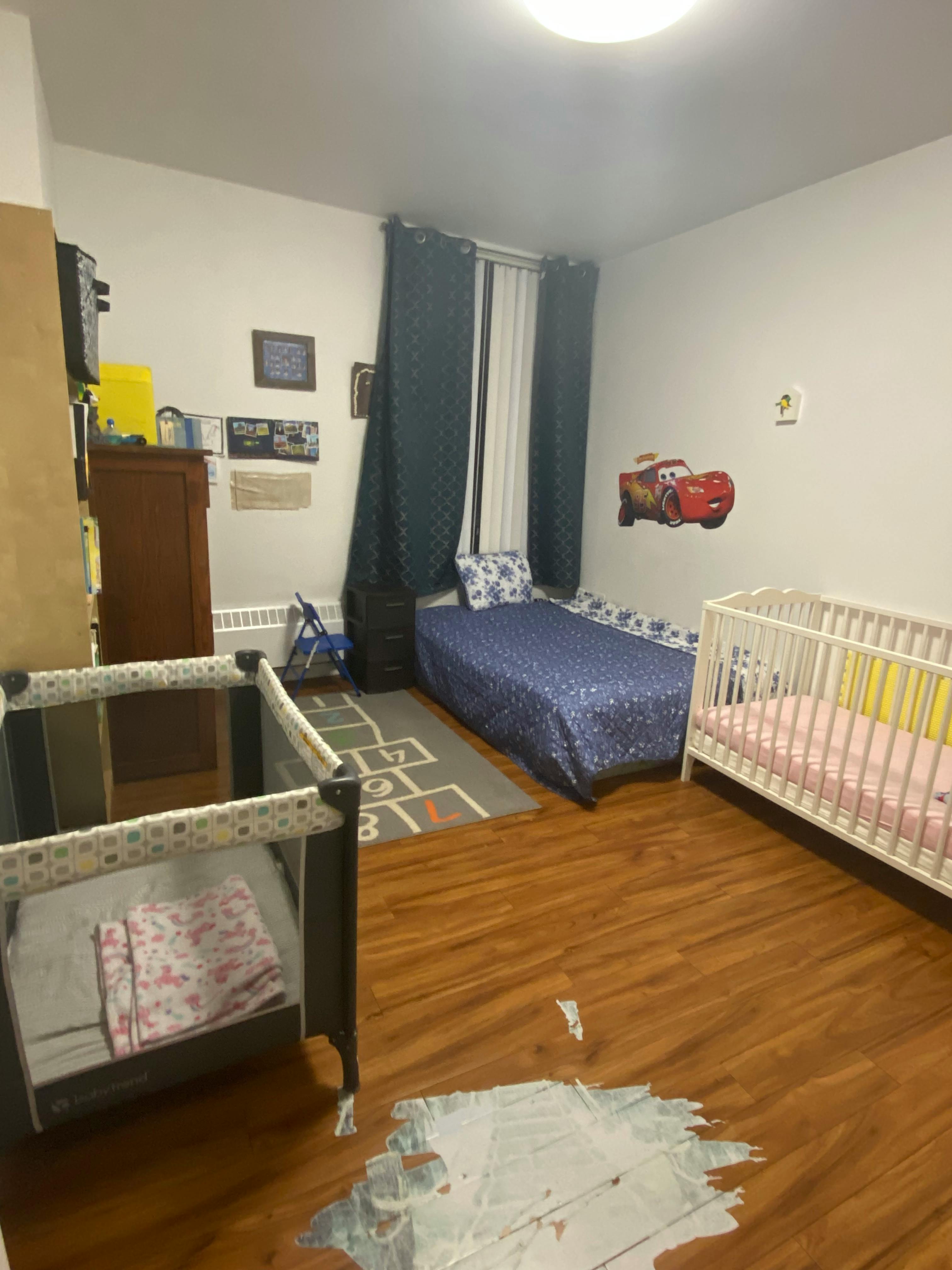 Bedroom with a bed, a white crib, and a playpen