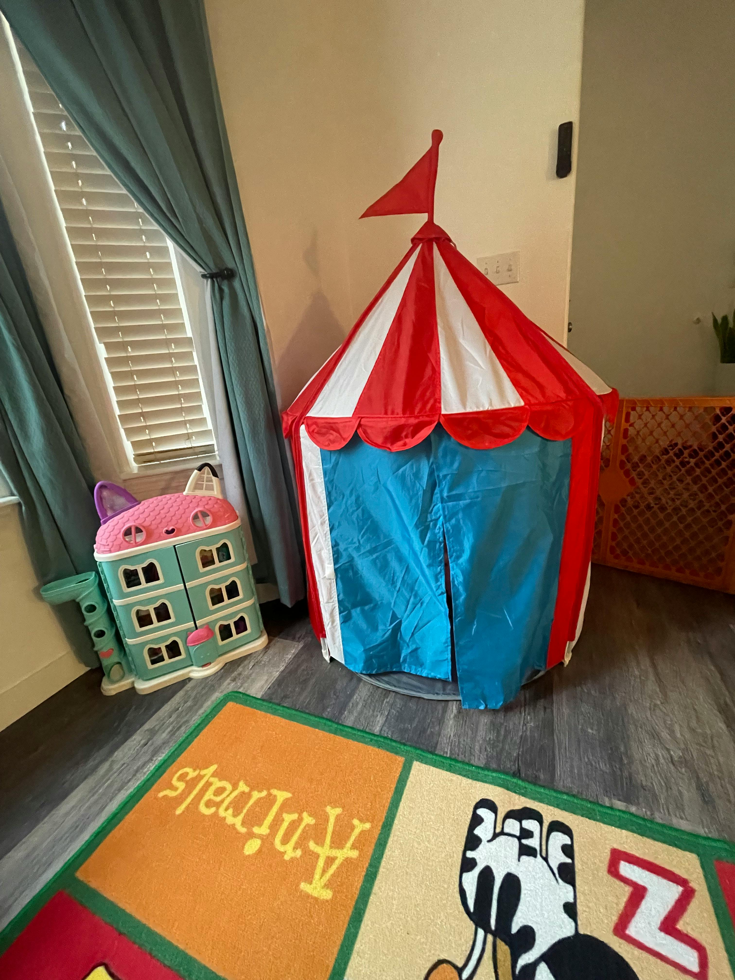Red and white striped play tent with a blue base and white entrance