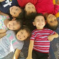 Seven children lying in a circle with heads together