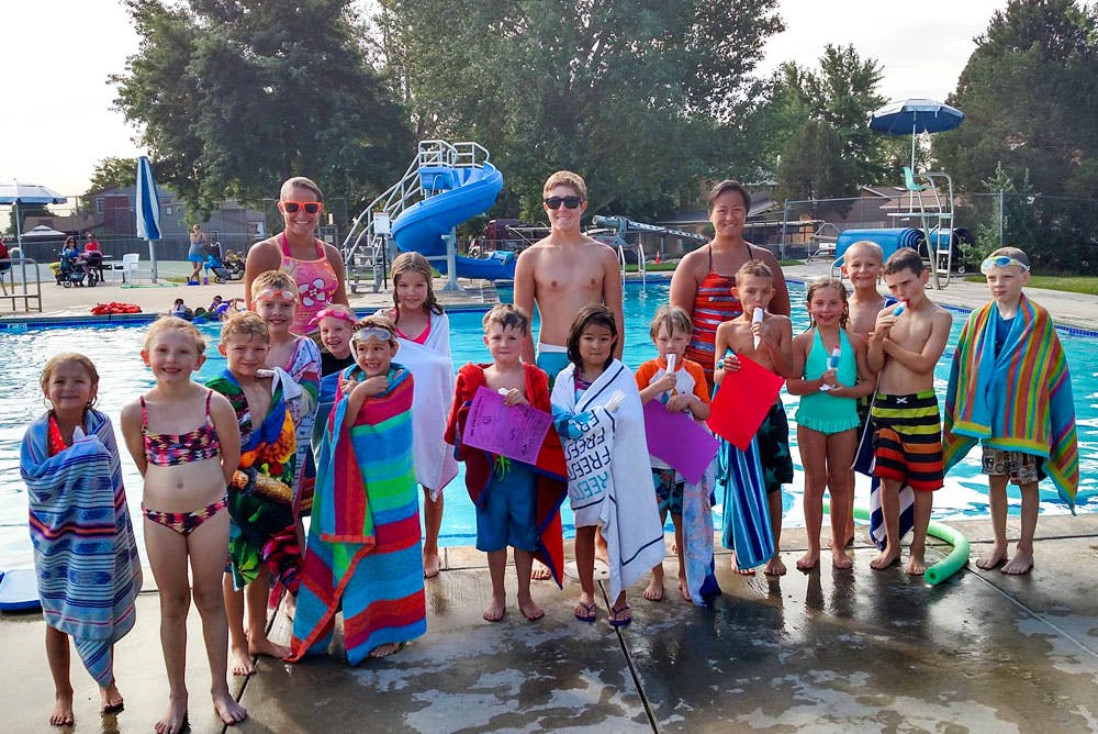 Group of children and adults standing by a swimming pool