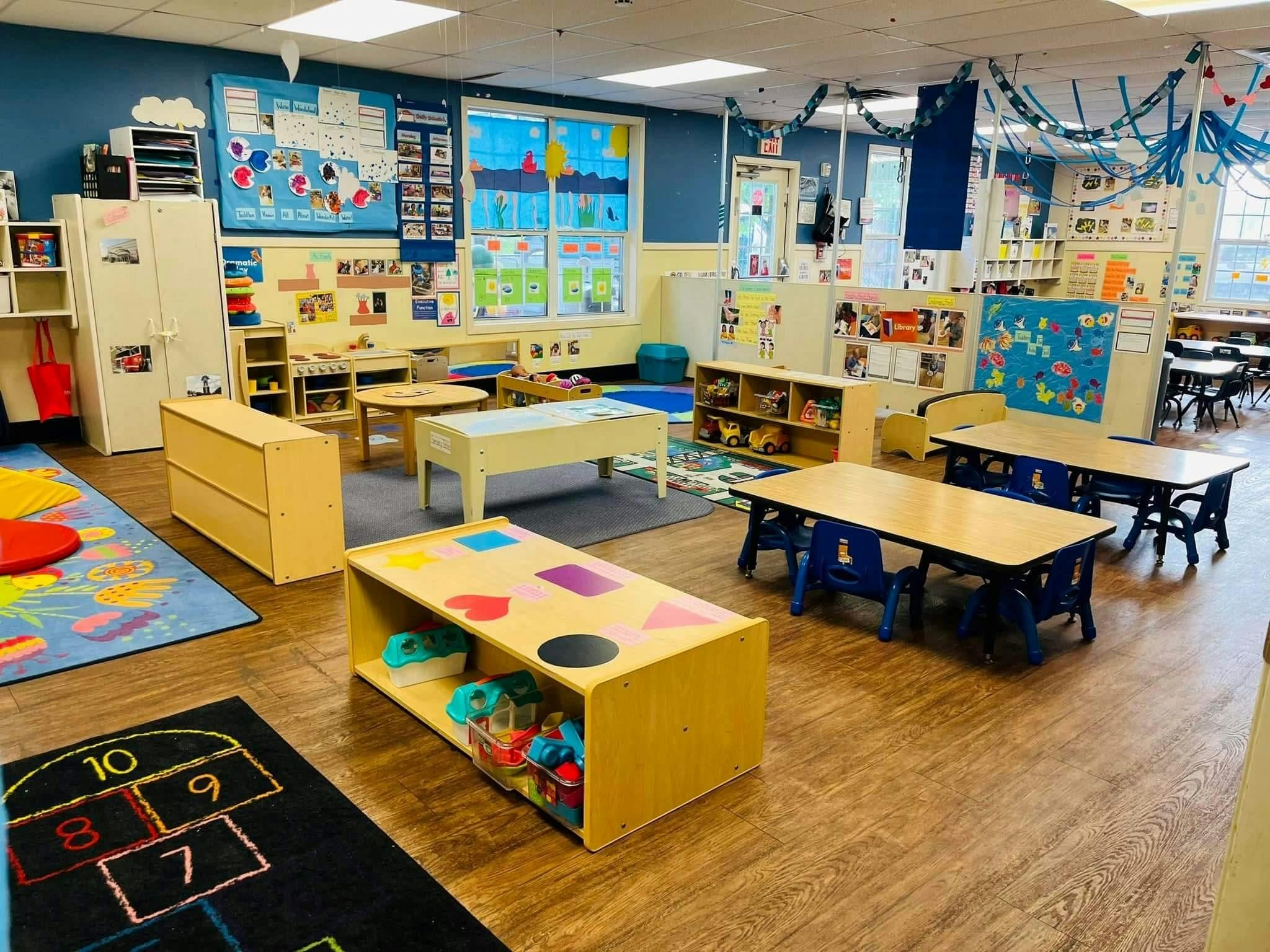 An empty early childhood classroom with various activity stations and small tables