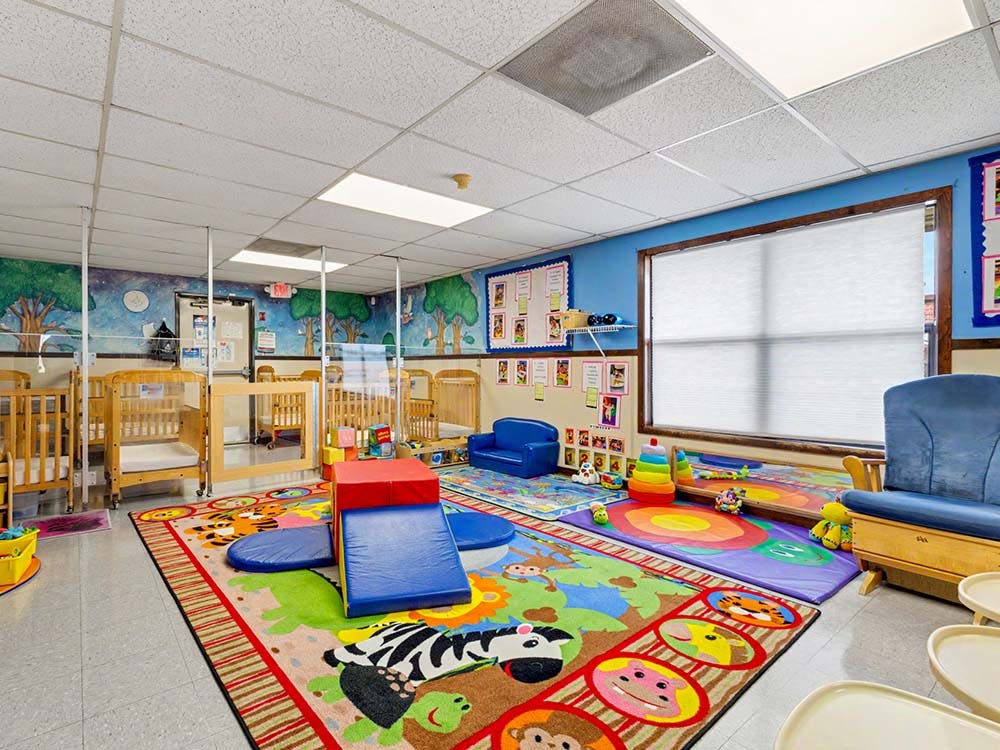 Classroom with cribs, play mats, and soft play equipment