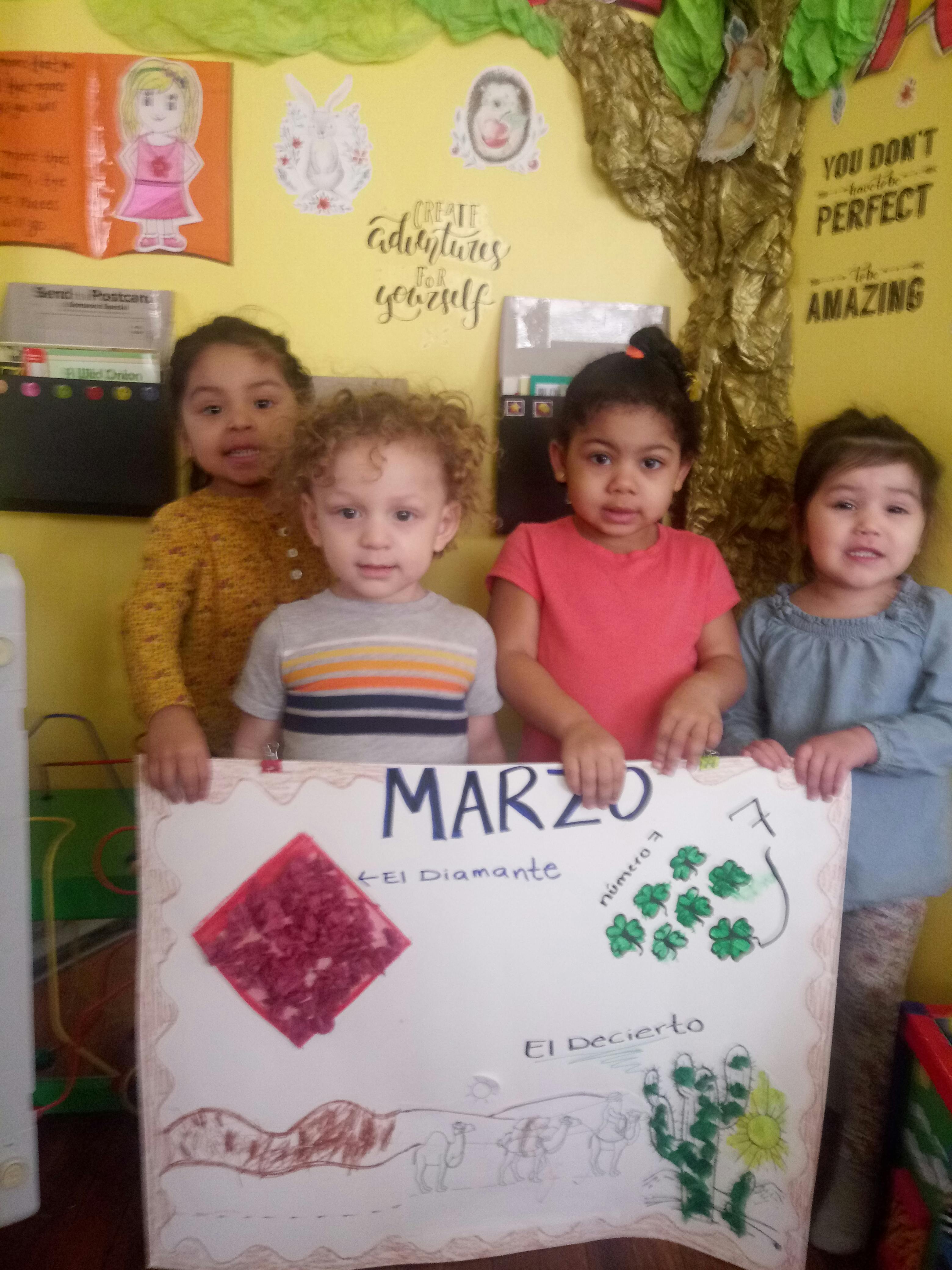 Four children holding a poster with "MARZO" written on it