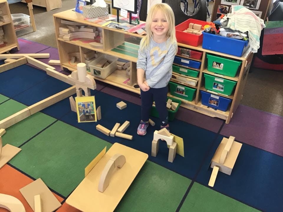 Child standing in a classroom with wooden blocks