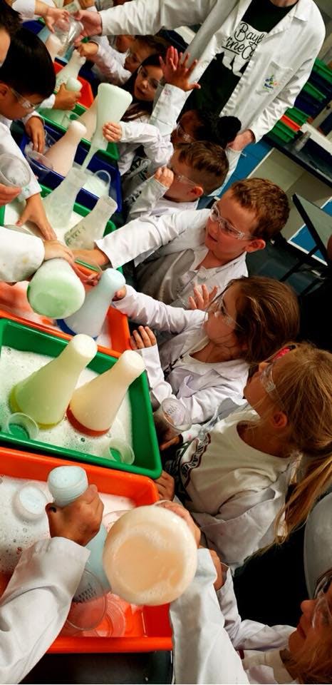 Children in lab coats and safety glasses doing a science experiment