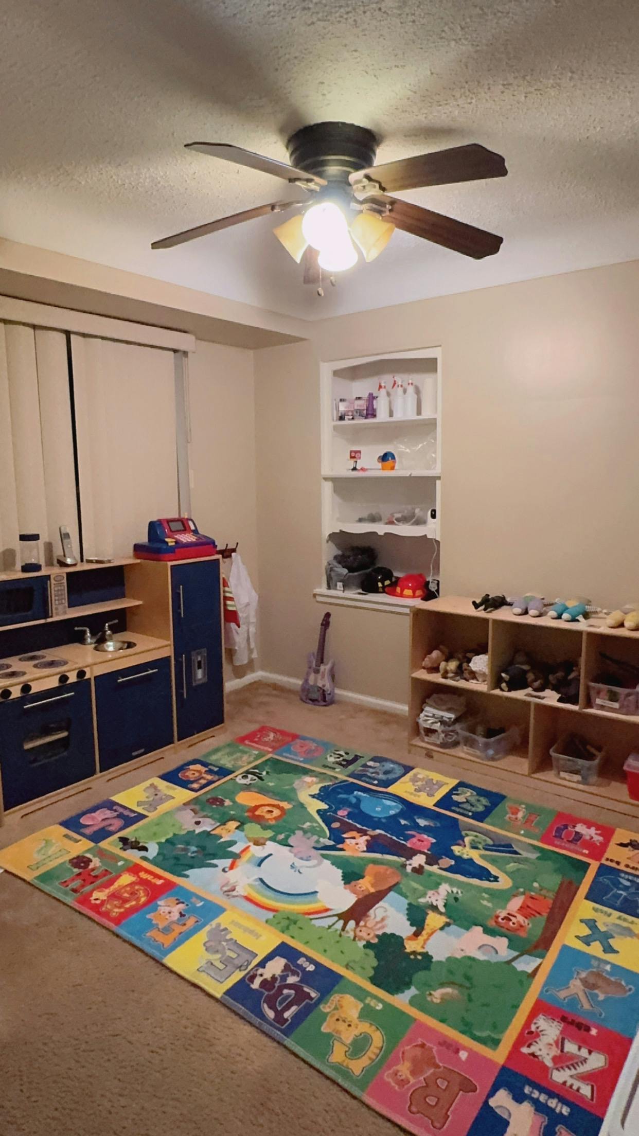 Children's play kitchen and alphabet rug in a room