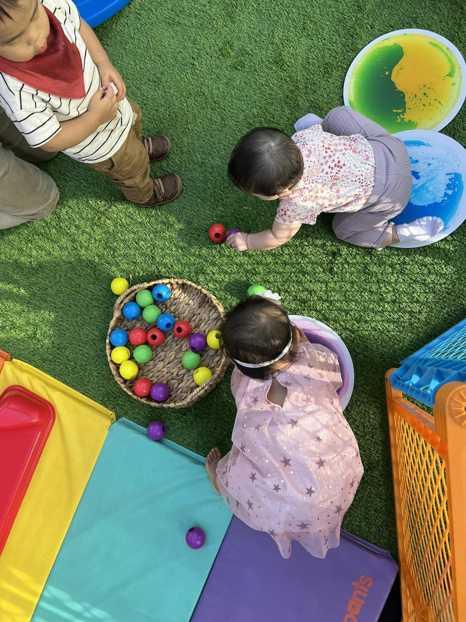 Children playing with colorful balls on green turf and play mats