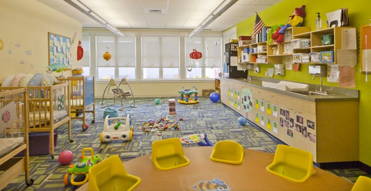 Playroom with cribs, toys on the floor, and a table with chairs