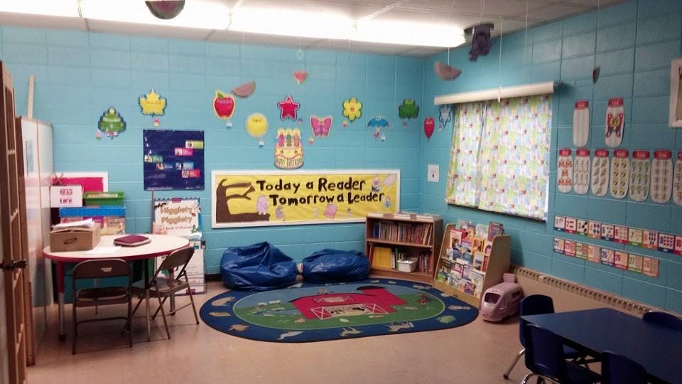 Classroom with colorful decorations, small tables, and a rug