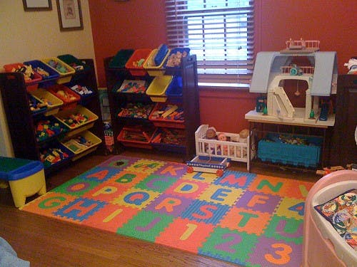 Playroom with toy storage, dollhouse, and alphabet mat