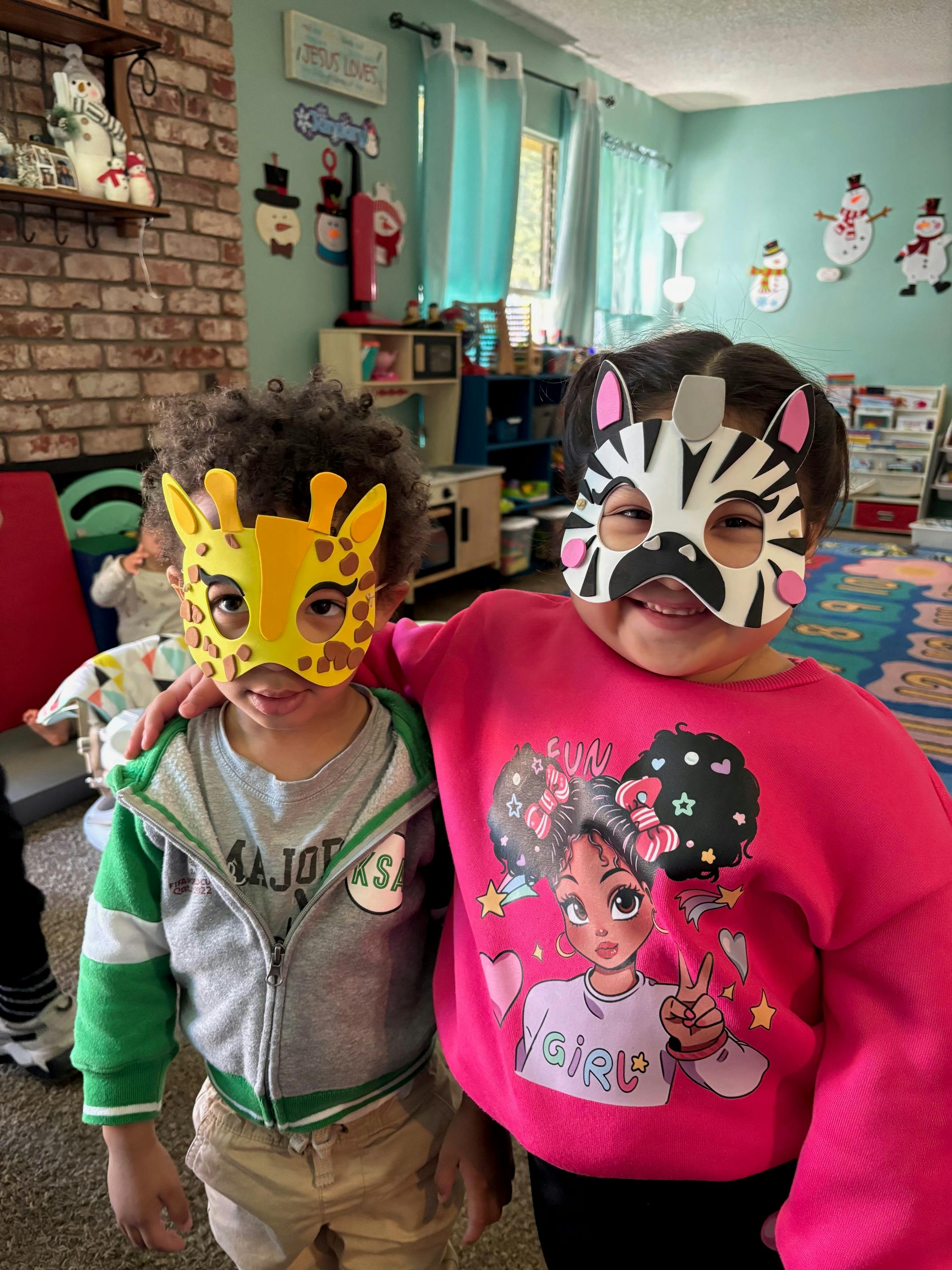 Two children wearing animal masks, one a giraffe and one a zebra