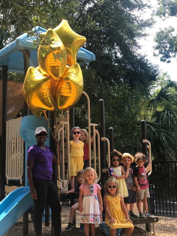Person and children on a playground with balloons